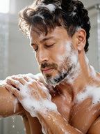 Shirtless Tiger Shroff massaging rich lather onto his neck and shoulder in the shower.