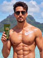 Tiger shroff in sunglasses at the beach holding PROWL aqua gel sunscreen, with a swatch of lotion applied to his chest.