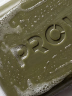 Close-up of the PROWL logo embossed on a wet, richly lathered bar of PROWL Detan Body Soap.